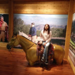 The girl is sitting on the man-made horse
