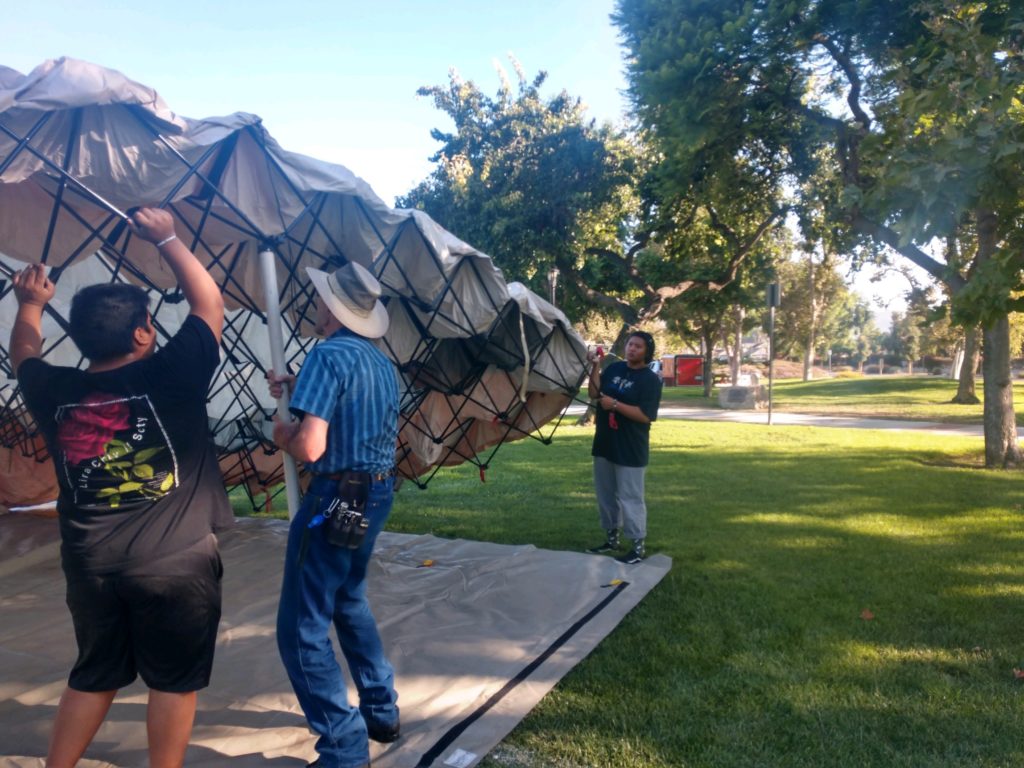 Three men are installing the big tent