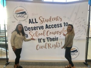 Two women are standing near the banner of California Association of School Counselors