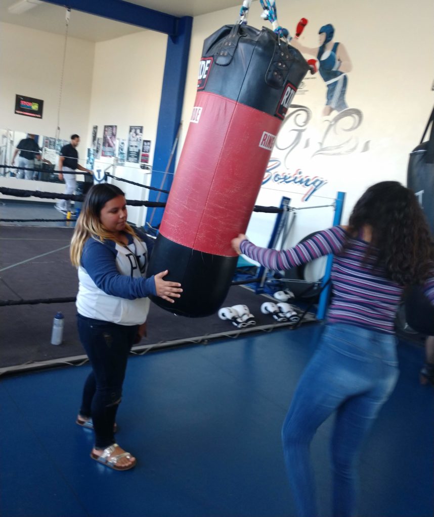 Girl beats a punching bag with her left hand