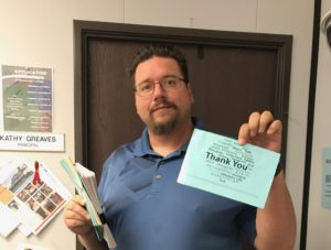 Man with glasses is showing "thank you" card
